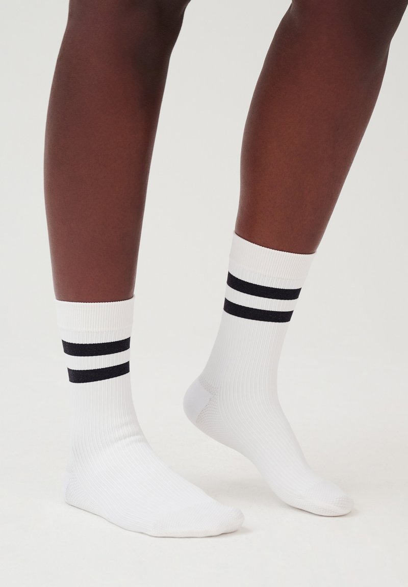 Weiße Sportsocken mit schwarzen Streifen oben, ausgestattet mit einer gerippten Textur und im Knöchellängen-Design. Geeignet für lässige Kleidung.
