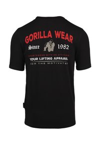 Zwarte katoen T-shirt met opvallende rode en witte tekst op de achterkant, inclusief "GORILLA WEAR" en "Sinds 1982," met een gorilla-afbeelding.