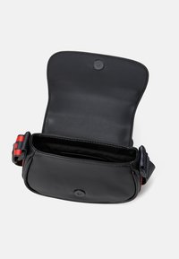 Borsa a tracolla nera in pelle con chiusura a scatto, tracolla regolabile a righe rosse e blu, e un interno liscio e non foderato.