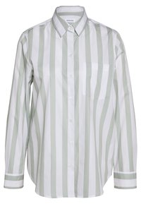 Skjorta med knäppning som har vertikala ränder i ljusgrön och vit, med en bröstficka, långa ärmar och klassisk krage. Tillverkad av bomull.