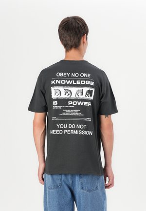 Sort bomulds t-shirt med stort hvidt tekst og grafiske design på ryggen, korte ærmer og en afslappet pasform.