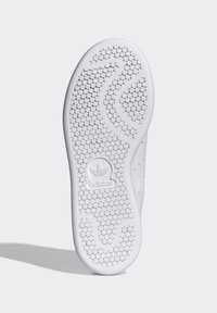 Hvit sneakersåle med et teksturert, bikubemønster, glatte kanter og en preget logo nær hælen. Ren, minimalistisk design.