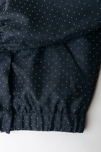 Tengerészkék szövet fehér pöttyökkel, rugalmas derékpánttal, sima textúrával és oldalsó zsebrészlettel.