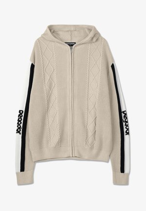 Beżowa dziergana bluza z kapturem, zapinana na zamek, z motywem splotu warkoczowego, czarno-białe paski na rękawach oraz wyszywany akcent na rękawie.