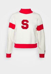 Bílá mikina s vysokým červeným límcem a červenými akcenty. Obsahuje velké červené písmeno "S" a kontrastní červené pruhy na rukávech.