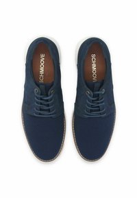 Zapatos azul marino con textura de malla y acentos lisos. Presentan una punta redonda, diseño de cordones y una suela de goma blanca con borde marrón.
