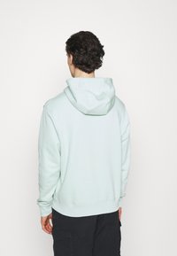 Sudadera de un suave verde menta con capucha ajustable, puños y dobladillo acanalados. Hecha de una tela suave y texturada; presenta un corte holgado.