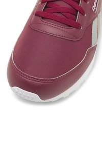 Bordo spalvos sportbačiai su lygiu sintetiniu viršumi, balta gumine pado dalimi, tekstūruota paviršiaus apdaila ir derančiomis raištelėmis. Yra subtilus prekės ženklinimas ir siuvimas.