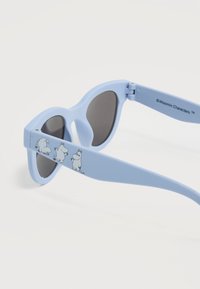 Γαλάζια γυαλιά ηλίου με σκούρους φακούς που διαθέτουν τρεις μικρές απεικονίσεις χαρακτήρων Moomin στο σκέλος του βραχίονα.