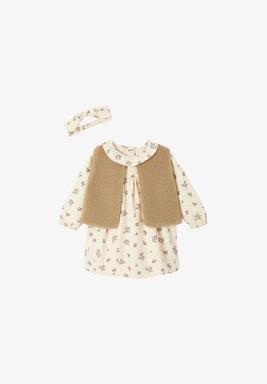 Beige Kleid mit floralem Druck, das einen gerafften Kragen und lange Ärmel hat, kombiniert mit einer weichen braunen Fleece-Weste und einem passenden Kopfband.