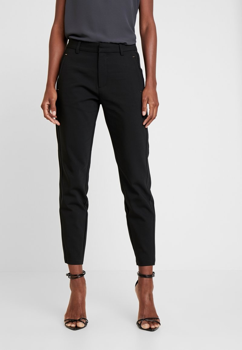Pantalon noir sur mesure à coupe slim, avec poches latérales et accents dorés. Confectionné dans un tissu lisse et léger.