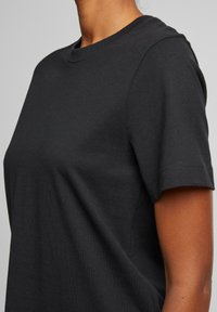 Zwarte katoenen t-shirt met ronde hals, korte mouwen en een zachte textuur. Heeft een gladde, gelijkmatige afwerking zonder zichtbare patronen of accenten.