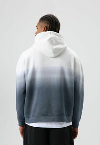 Capuchontrui met een verloopontwerp, van wit naar grijs. Gemaakt van zachte stof met een ontspannen pasvorm en geribde manchetten.