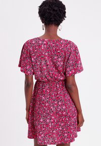 Short-sleeve, floral dress featuring a pink and red pattern, elastic waistband, and a flared skirt. Lightweight fabric with a soft texture.