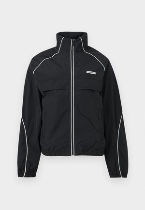 Veste de jogging noire à fermeture éclair avec passepoil blanc, col montant, poignets élastiques et logo "tommy jeans" sur la poitrine gauche.