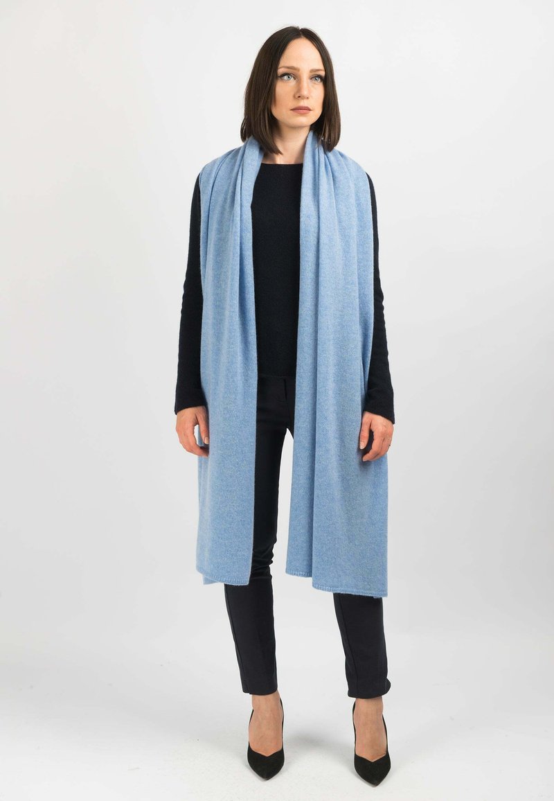 Lyseblå scarf lavet af blødt stof, der hænger elegant omkring halsen. Har en glat overflade og rene kanter, og er parret med en sort top og bukser.
