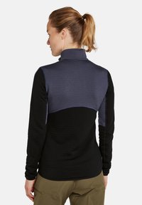 Camiseta de manga larga con cuello alto, que presenta un cuerpo negro y un panel superior azul oscuro. Textura suave con detalles de costura en contraste.