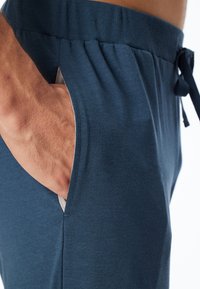 Navyblaue Baumwollmischung-Jogginghose mit elastischem Bund. Verfügt über eine Seitentasche und ein Kordelzugband. Glatte Textur, lässiges Design.