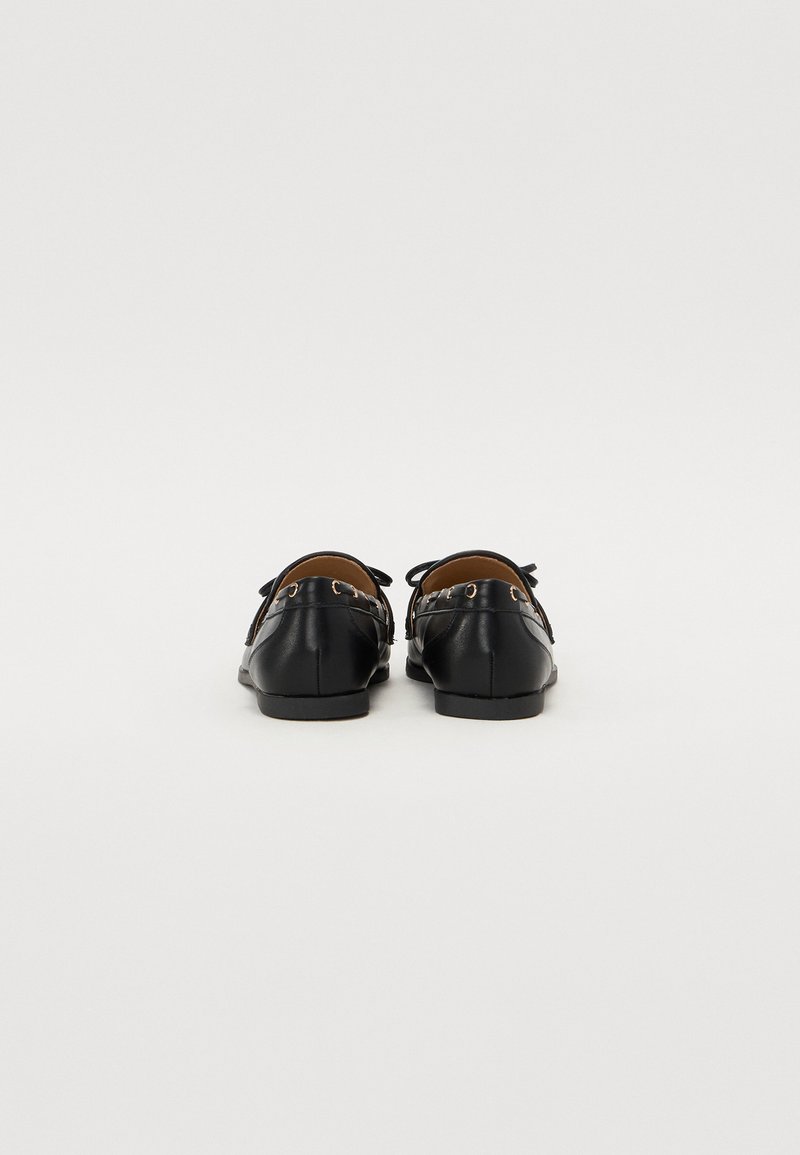 Ballerine in pelle nera con finitura liscia, dotate di piccole decorazioni a forma di fiocco e hardware in tono oro, punta arrotondata e suola piatta.