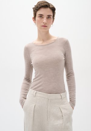 Long-sleeve, light taupe top made of soft, lightweight fabric with a scoop neckline, paired with high-waisted, beige linen trousers.