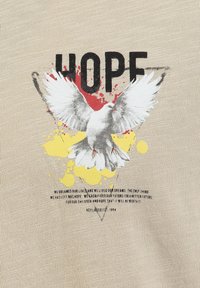 Paloma blanca con las alas extendidas sobre salpicaduras rojas y amarillas, la palabra "ESPERO" en letras mayúsculas negras arriba, sobre una tela texturizada beige.