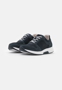 Schwarze Sneakers aus Netz- und Wildledermaterialien, mit weißen Schnürsenkeln, gepolsterten Sohlen und einem runden Zehendesign. Verfügt über kontrastierende Texturen und Akzente.