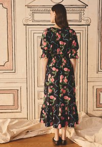 Rochie neagră florală cu mâneci bufante, talie elastică și tiv cu volane. Decorată cu trandafiri roz și viță de vie verde pe un fundal întunecat.