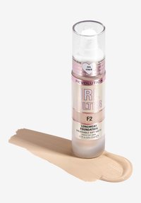 Revolution IRL Filter F2 langvarig foundation i en klar pumpeflaske, med en myk matt beige nyanse på en swatch ved siden av.