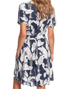 Marineblauwe jurk met witte botanische print, korte mouwen, getailleerde taille en zakken. Lichtgewicht stof valt in een uitlopende rok.