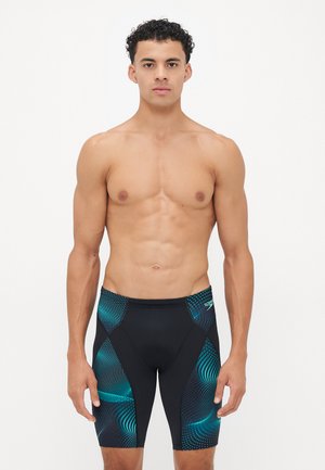 Shorts de bain noirs avec des accents de motif vagues turquoise. Fabriqués en matériau extensible, conçus pour la performance et le confort.