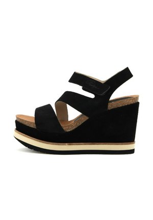 Sandalo con tacco a cuneo in suede nero con sottopiede in sughero, dotato di due cinturini regolabili e suola in gomma beige con base nera a contrasto.
