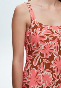 Floral dress featuring pink and white flower patterns on a brown background, made of lightweight fabric with wide shoulder straps.