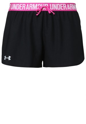 Kobieta ubrana w czarny sportowy biustonosz i czarne szorty Under Armour z różową gumą w talii oraz czarne buty sportowe, stojąca na szarym tle.