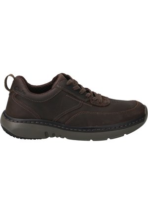 Brown leather sneakers with a rounded toe, textured accents, and a cushioned gray rubber sole. Features laces and a rear pull tab.