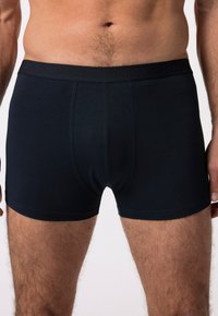 Tmavě modré boxerky vyrobené z měkké tkaniny, s elastickým pasem, na kterém je jemně vynikající název značky, s těsným střih a hladkou strukturou.