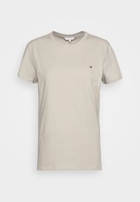 Camiseta de algodón beige con cuello redondo, mangas cortas y un pequeño logo en el pecho. Textura suave, ajuste casual y diseño sencillo.