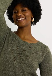 Suéter de punto verde aceituna con patrón texturizado y detalles de punto abierto. Cuello redondo, mangas largas y un acabado suave, ligeramente brillante.