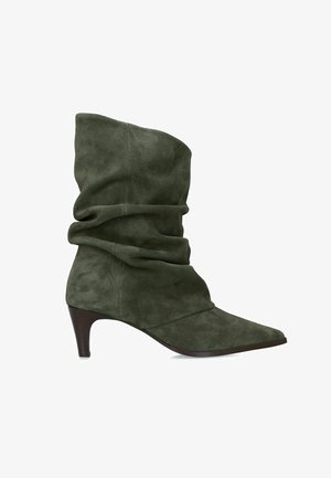 Donkergroene suède midkuit laars met losse pasvorm, puntige neus en smalle bruine hoge hak.