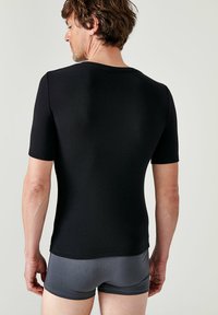 Maglietta nera a maniche corte aderente realizzata in tessuto morbido, con scollo rotondo e design della schiena senza cuciture, abbinata a boxer grigi.