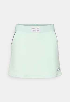 Lichtgroene tennisrok met een zachte, gladde textuur, elastische tailleband en een logolabel aan de voorkant. Heeft marineblauwe accenten aan de zijkanten.