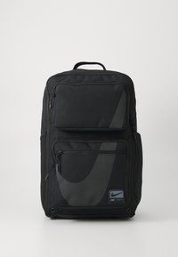 Sac à dos noir en tissu durable avec plusieurs compartiments zippés. Présente un design et un logo Nike en gris proéminent.