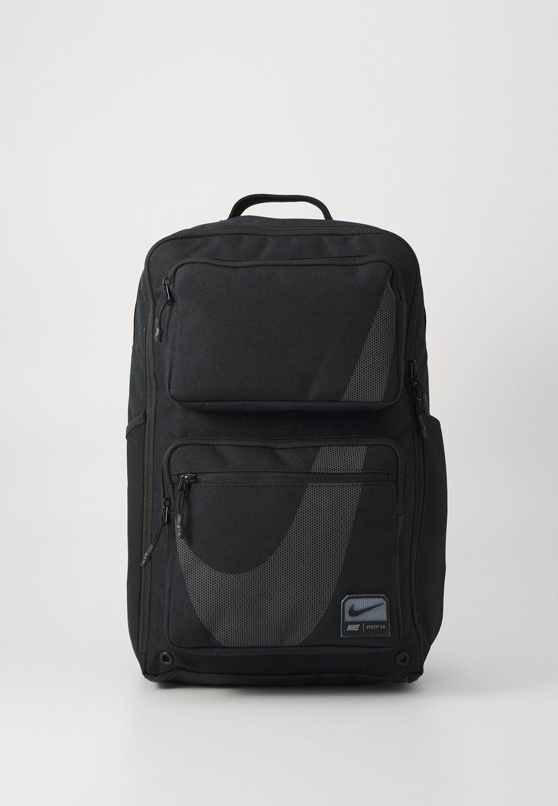 Sac à dos noir en tissu durable avec plusieurs compartiments zippés. Présente un design et un logo Nike en gris proéminent.