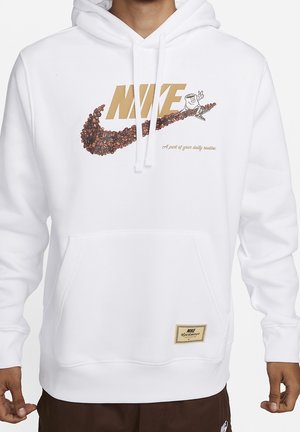 Bílá mikina s kapucí s béžovým nápisem "NIKE" a kávovým fazolovým logem, s malou postavičkou držící znamení míru na skejtu a textem "Součástí tvé denní rutiny."