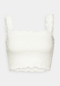 White cropped top with textured smocking, square neckline, and ruffled straps. Hem features a wavy edge for added detail.