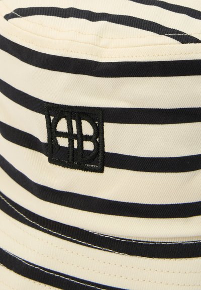 Tessuto a righe bianche e nere con un logo quadrato nero ricamato che presenta lettere intrecciate sulla superficie del tessuto.