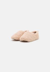 Fuzzy beige slippers with pointed toes, made of soft, textured material. Interior lining is plush; minimalistic design with no visible hardware.