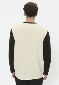 Langsleeve shirt met een crèmekleurig lijf en zwarte mouwen. Gemaakt van katoen, heeft het een ronde halslijn en een ontspannen pasvorm.