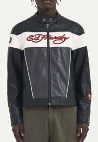 Giubbotto in pelle bianco e nero con colletto alla coreana, zip frontale, ricamo "Ed Hardy" in rosso e una patch sulla manica sinistra.