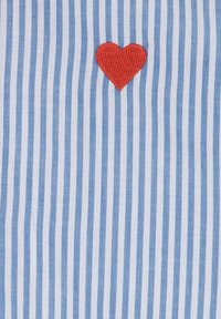 Blue and white striped fabric with a red embroidered heart centered on the design. The texture is smooth and flat.
