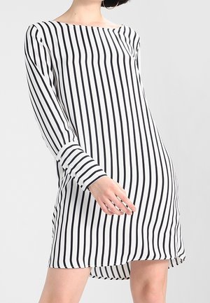 Biała sukienka z pionowymi czarnymi paskami, długimi rękawami, łódkowym dekoltem i luźnym krojem, z lekko zaokrąglonym dołem.